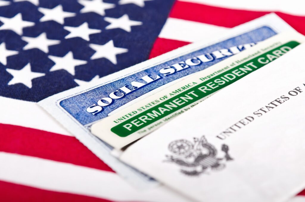 Close-up of various U.S. immigration documents including a Welcome to the United States folder, part of a U.S. visa, and a Green Card, representing the legal documentation for new permanent residents.
