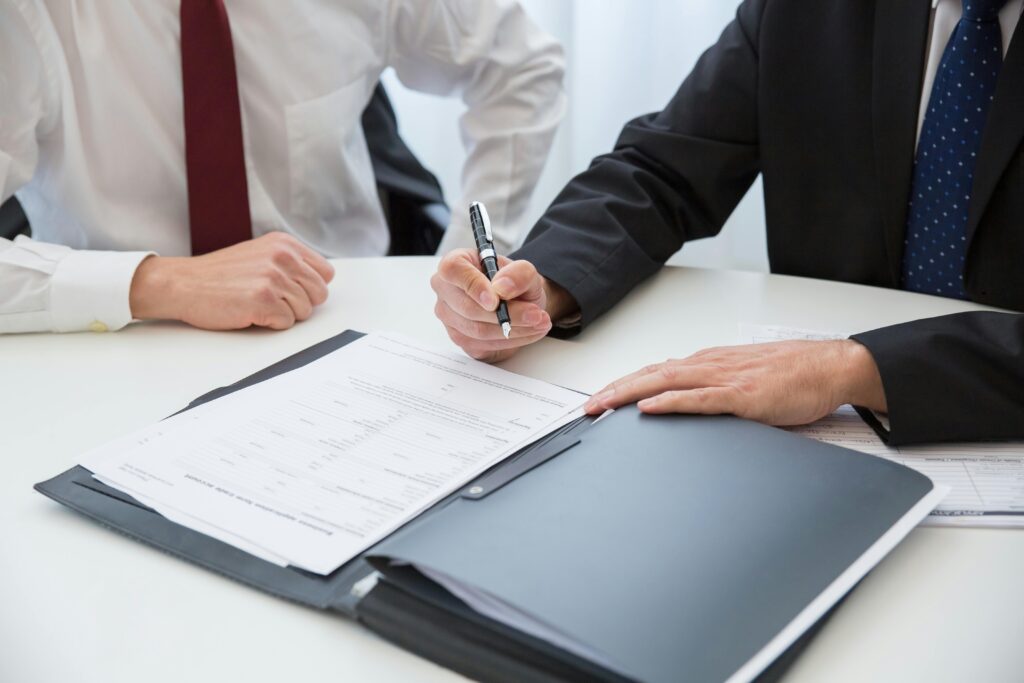 Close-up view of two businessmen in a formal meeting, with one person signing a document.